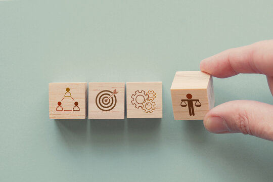 Hand holding wooden block with Ethical icons, business ethics and corporate compliance concept