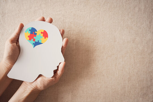 Hands holding jigsaw puzzle heart shape in brain, Autism awareness, handicap disorder, spectrum head concept, World Autism Awareness Day