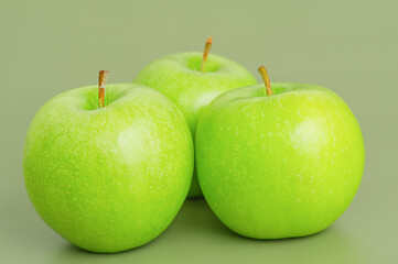 Three green apples. Apple fruit on a green background.