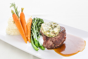 A plate of food with a steak, carrots, and broccoli