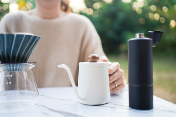 Asian woman making a handcraft drip coffee at the camping ground.