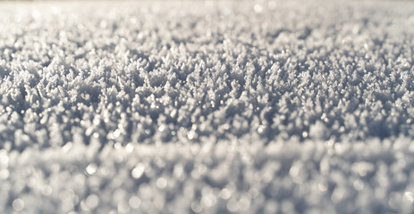 Macro view of intricate snow crystals shimmering in sunlight, showcasing natural frost patterns and winter textures in detail.