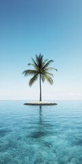 Fototapeta premium Solitary palm tree on a small island in the middle of a calm ocean under a clear blue sky.
