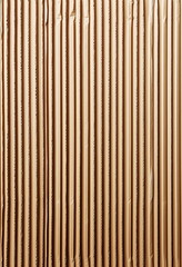 Close-up of the textured surface of the wavy vertical line pattern of brown corrugated cardboard. 