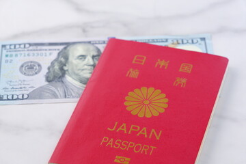 Fototapeta premium 日本のパスポートと、ベンジャミン・フランクリンが描かれたアメリカ合衆国ドル（US＄）の100ドル紙幣で、海外旅行を計画しているイメージ 