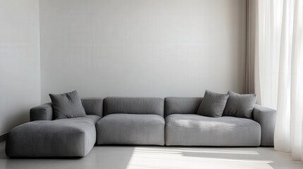 A large gray couch with pillows on it sits in a room with a white wall