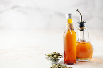 Pumpkin oil and seeds in bottles on a bright background.