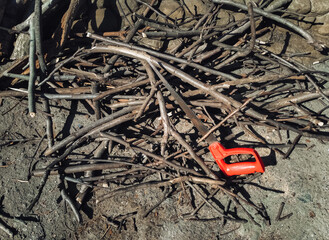 A pile of thin hazel firewood, cut and sawn from trees for kindling. A small saw lies nearby, symbolic of handicraft.