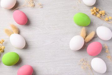 White easter eggs with bunny rabbit ears and colorful easter eggs on white background with copy space, Top view