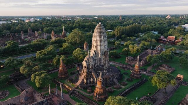 This drone footage showcases the majestic ruins of Ayutthaya, Thailand. Surrounded by lush greenery, the ancient temple's architecture and towering spire reflect the grandeur of its historic past.