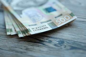 Many five hundred hryvnia money bills lies on wooden background. Ukrainian national currency close...