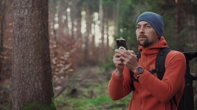 Maps outdoors while hiking. Hiker use smartphone to navigation in forest via app cartography. Trekking routes by smartphone. Traveller navigates his way through woods using GPS. Explore and hike. 