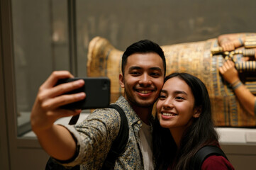 Young Southeast Asian couple takes selfie near ancient artifact