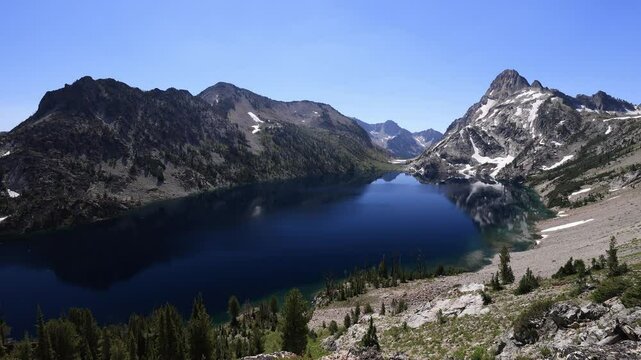 Sawtooth Lake in Idaho's Sawtooth National Recreation Area reflects the sunny summer sky. Mt. Regan rises in the distance, while the calm, still waters enhance the peaceful alpine setting.