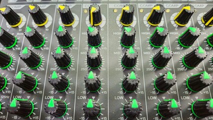 Close-up faders, knos and buttons of audio mixer in broadcast studio.
