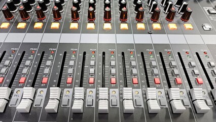 Close-up faders, knos and buttons of audio mixer in broadcast studio.