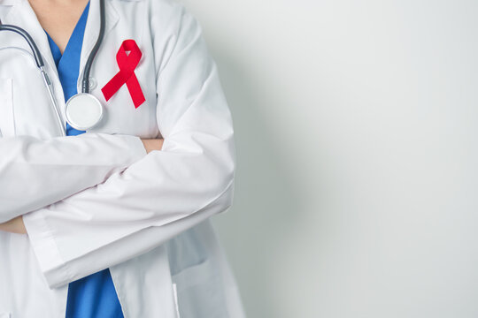 Doctor with Red Ribbon for December World Aids Day, acquired immune deficiency syndrome, multiple myeloma Cancer Awareness month and National Red ribbon week. Healthcare and world cancer day concept