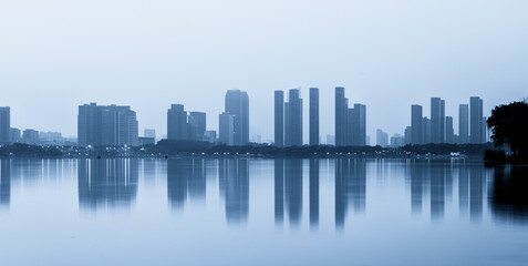 Obraz premium Tranquil Urban Skyline Reflected in Calm Waters at Dusk