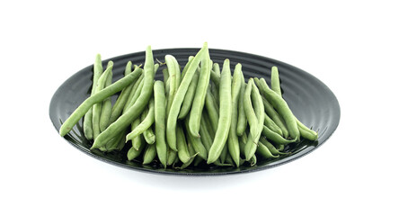Fresh green beans resting on a black plate on white background