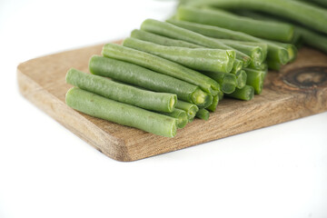 Fresh green beans resting on a wooden cutting board