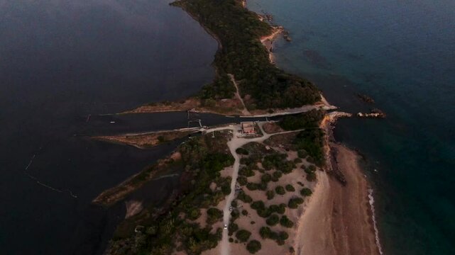 Aerial view of a sandy peninsula separating a calm lagoon from the ocean.