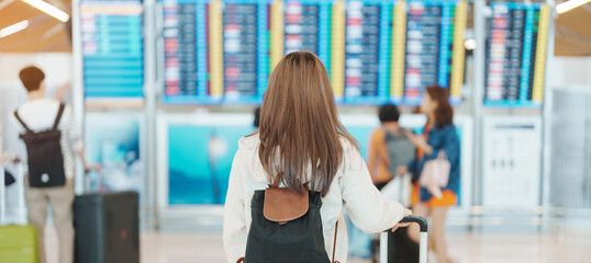 Young woman hand holding luggage handle before checking flight time in airport, Transport,...