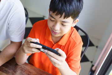 Asian father and son with mobile phone playing games together dad spend time with children family.