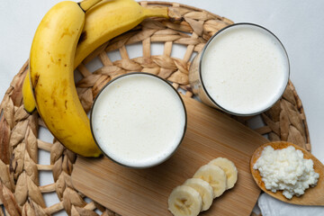 Bebida de kéfir fermentada con probióticos, granos kéfir sobre una cuchara de madera, kéfir preparado con banana. 