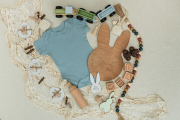Minimalist Easter Pregnancy Announcement Flat Lay with Blue Baby Bodysuit, Wooden Bunny Head,...