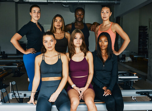 Diverse group of fit young women in sportswear standing confidently after an exercise class together in a pilates gym