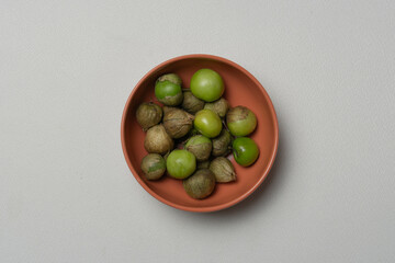 Tomatillo, miltomate en un cuenco sobre un fondo blanco, ingredientes de cocina. 