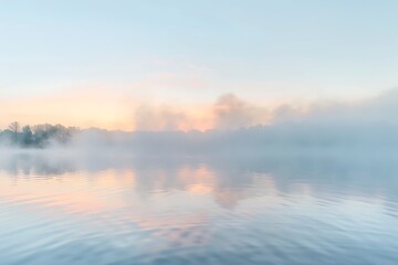 Obraz premium Soft pastel sunrise colors reflected on a still lake, shrouded in a light morning mist. Peaceful, serene atmosphere. Calm water, hazy sky.