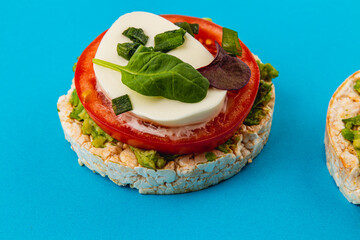 Rice cakes with mozzarella avocado spinach onion on a blue background