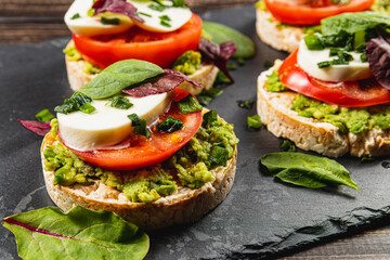 Rice cakes with mozzarella, avocado, spinach, onion on a stone on a wooden table