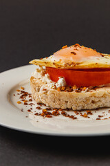 Sandwiches with egg on rice bread on a white plate on a black background closeup