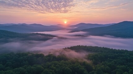 Obraz premium The calm of dawn settles over misty mountains, as the rising light gently filters through layers of fog.