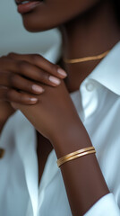 Elegant close-up of a black woman's hands adorned in gold jewelry and a white blouse