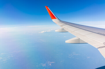 View from the airplane window at a beautiful cloudy sky and the airplane wing
