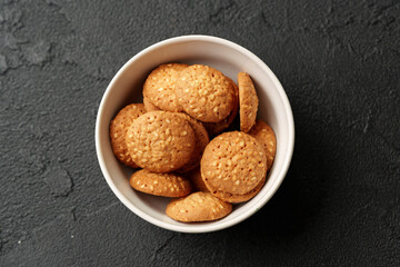 Freshly baked cookies in a white bowl against a dark textured background