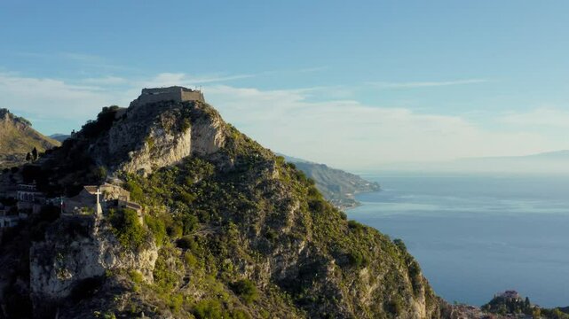 Aerial view of castle high up on a mountain's peak. Vast views of islands landscape. Mediterranean sea coastline.