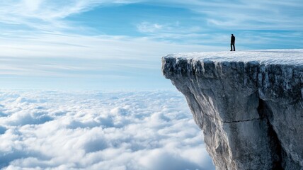 Person standing alone on cliff above clouds with blue sky background