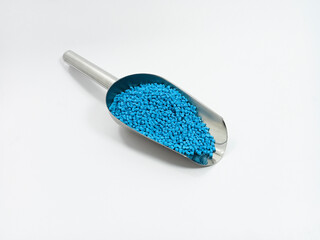blue masterbatch, polymer carries pigment in stainless steel spoon poured into white background...