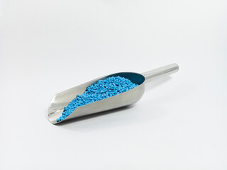 blue masterbatch, polymer carries pigment in stainless steel spoon poured into white background...