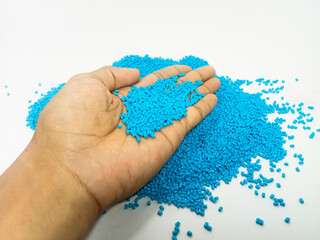 blue masterbatch, polymer carrying pigment in hand grip isolated on white background, suitable for...