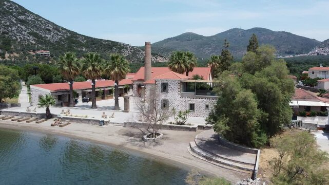 Zaira Hotel Estate stone building property and lounge area surrounding hills and coastal bay, Mytilene, Lesvos Island, Drone shot