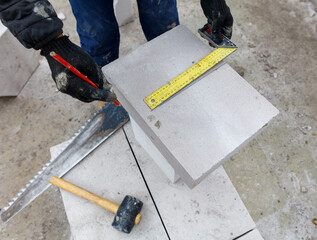 A man is measuring a block of concrete with a yellow tape measure