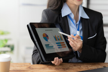 Businesswoman Presenting Data: Close-up shot of a businesswoman confidently presenting data on a tablet, showcasing her expertise and professionalism. The image exudes a sense of focus and clarity.