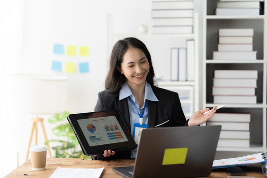Businesswoman Presenting Data:  A confident and professional businesswoman engages in a video conference, presenting data on a tablet with a friendly smile.