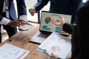 Business Professionals Analyzing Data: A diverse team of business professionals collaborates in a modern office setting, analyzing data on a laptop and documents.