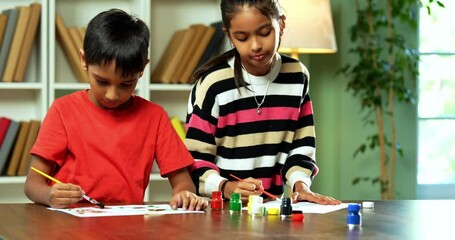 Indian Asian Cute Little Girl and Boy Siblings Playfully Painting on Canvas Using Brushes in a Small Isle at Home, Exploring Creativity and Art Skills, Sitting Together at Table in modern home - Powered by Adobe
